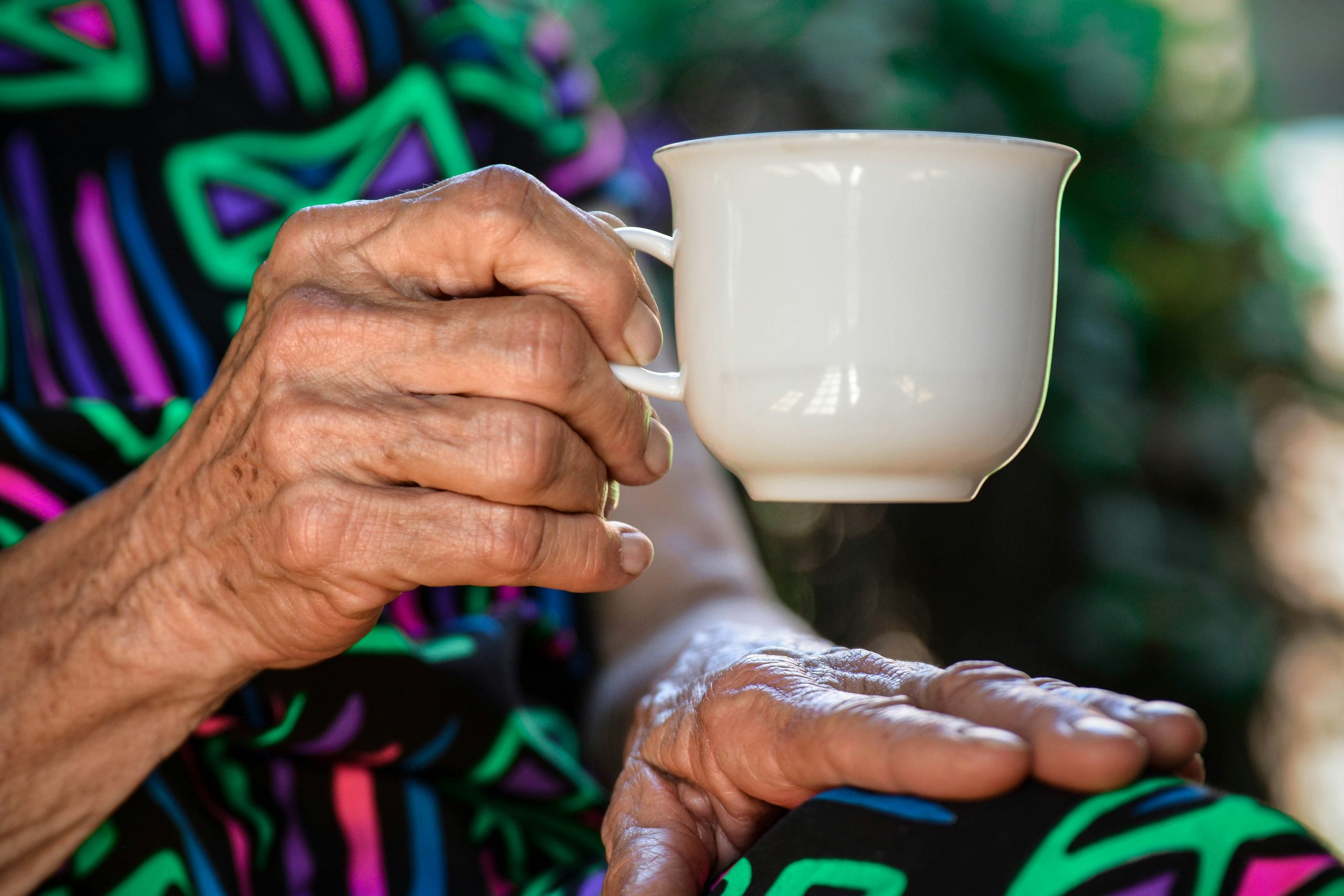 Caregiver handing a cup of tea to a resident
